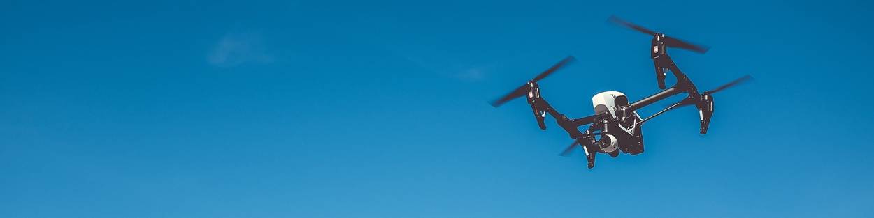 Een zwart-witte drone hangt in de lucht.
