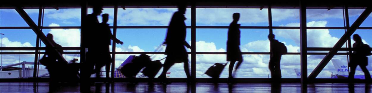 Passsagiers met koffer lopen over luchthaven Schiphol