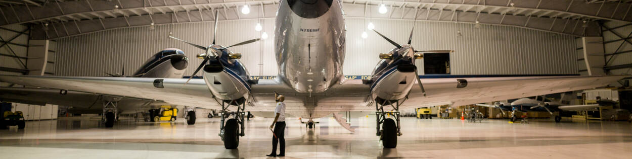 Man inspecteert vliegtuig in hangar