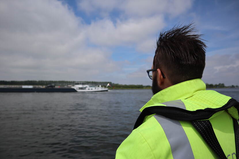 Inspecteur ziet binnenvaartschip varen op het water