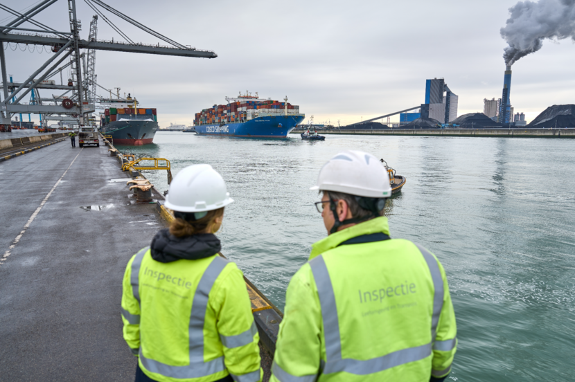 Inspecteurs op de kade van een zeehaven met containerschip en kolencentrale.