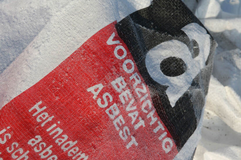 Een puinzak waarop staat "Voorzichtig, bevat asbest"