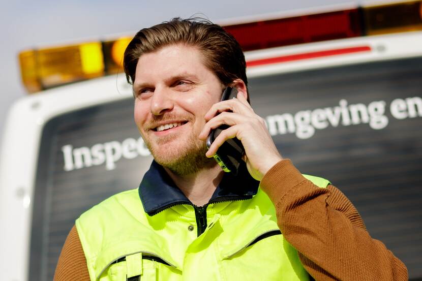 Mark van der Ham belt terwijl hij achter ene inspectie bus staat.