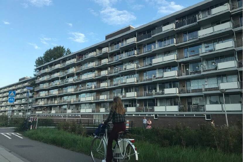Een fietser fietst langs een flat.